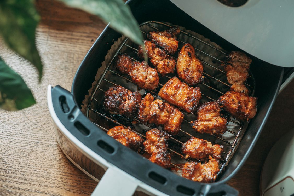 Crispy chicken pieces cooking in a modern air fryer basket