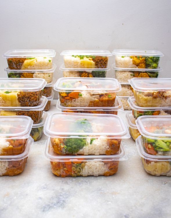 Meal prep containers filled with rice and vegetables on a counter