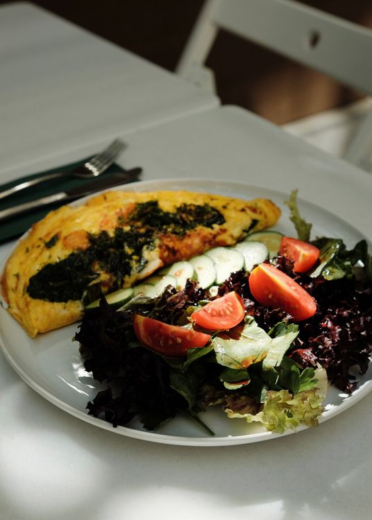 Sliced omelette with fresh greens and tomatoes on a plate