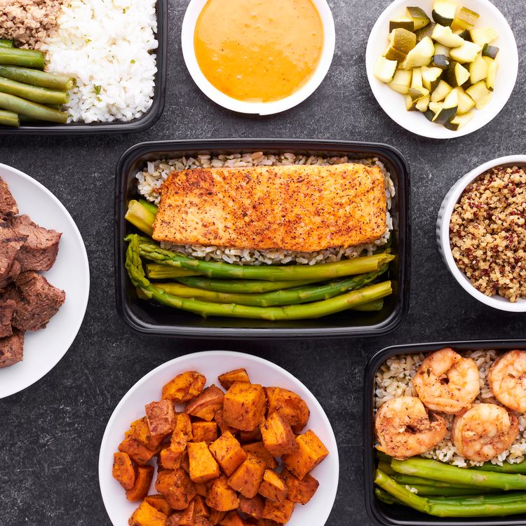 Flat lay of high-protein meal prep containers with salmon, shrimp, and asparagus