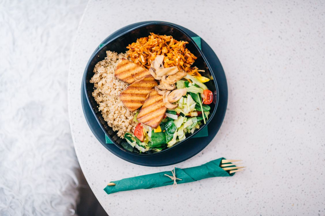 A bowl of roasted tofu, quinoa, and fresh vegetables